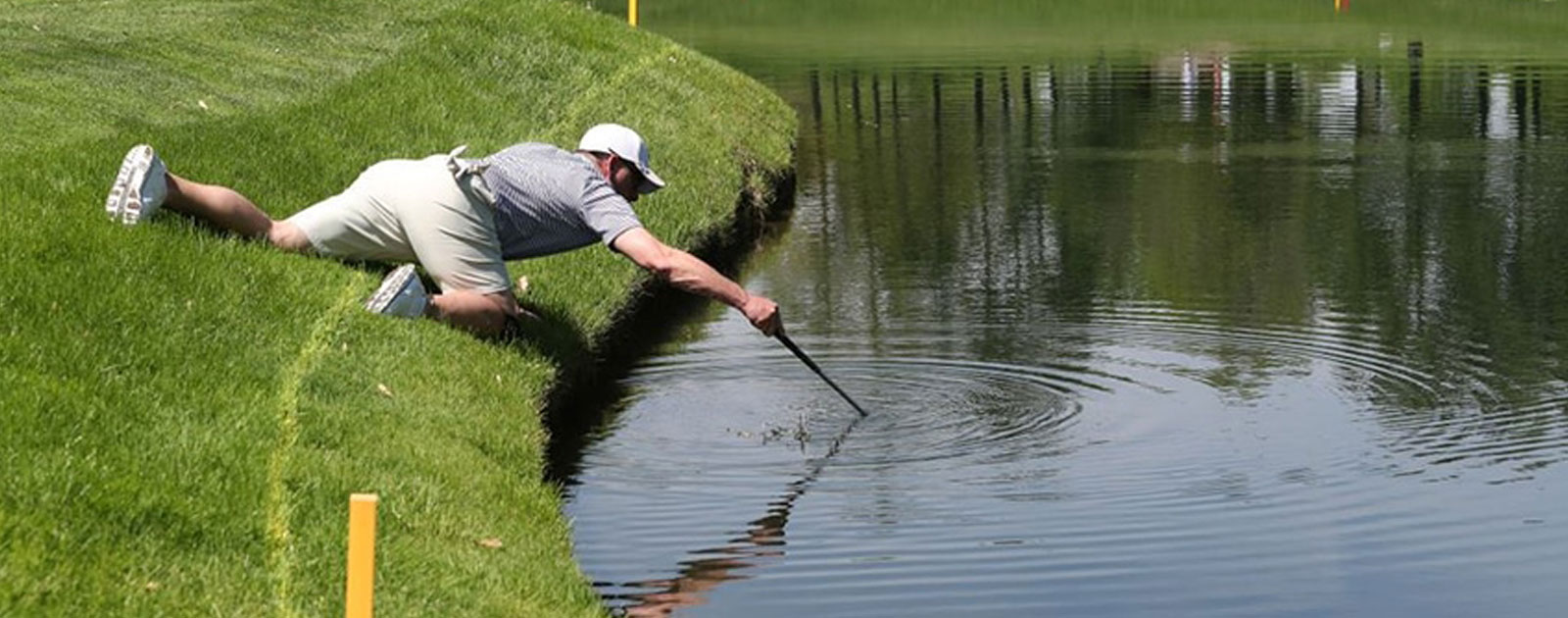 man looking for golf balls in water